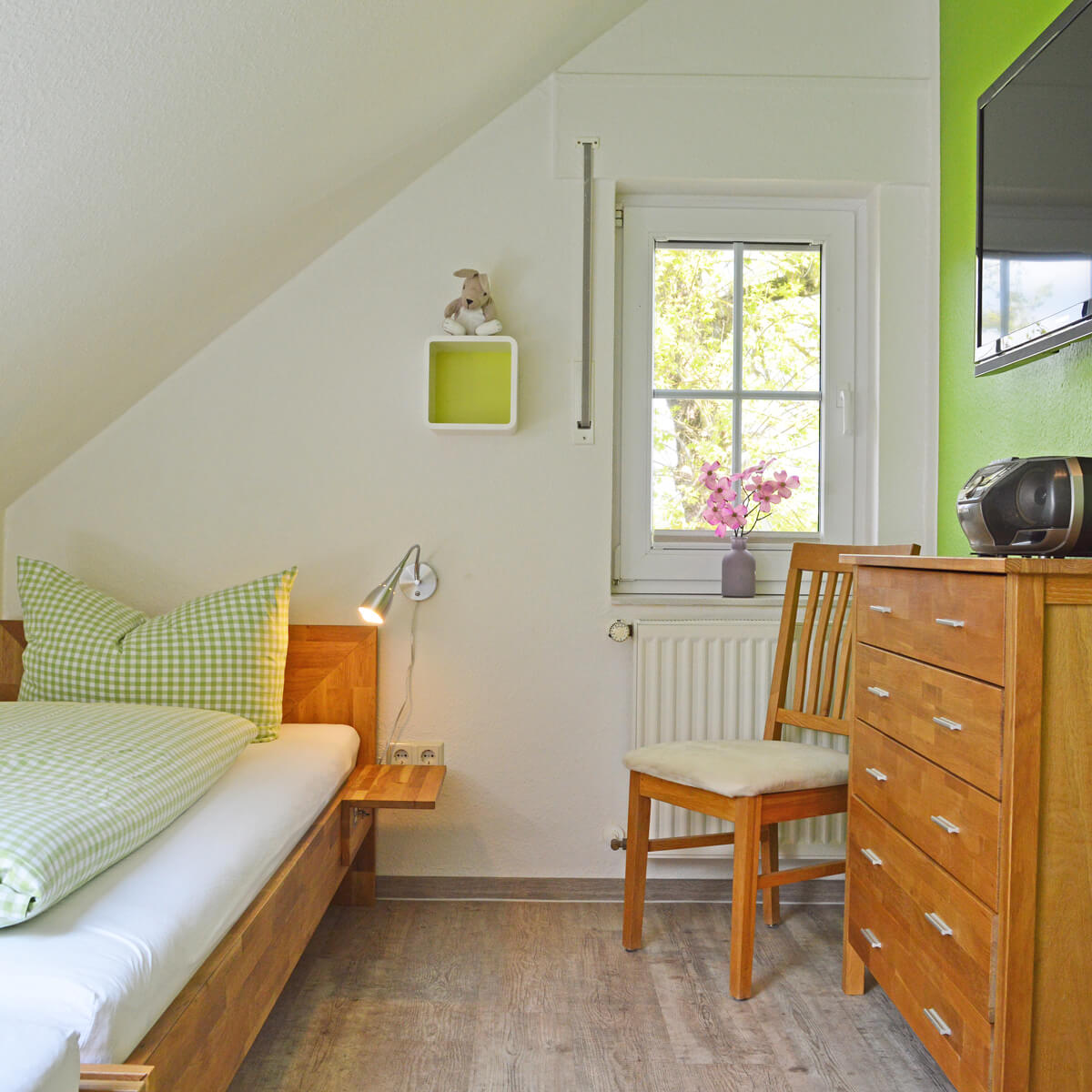 GemĂĽtliches Einzelzimmer im Ferienhaus Fox Lenz mit Holzbett, Kommode und Fensterblick ins GrĂĽne