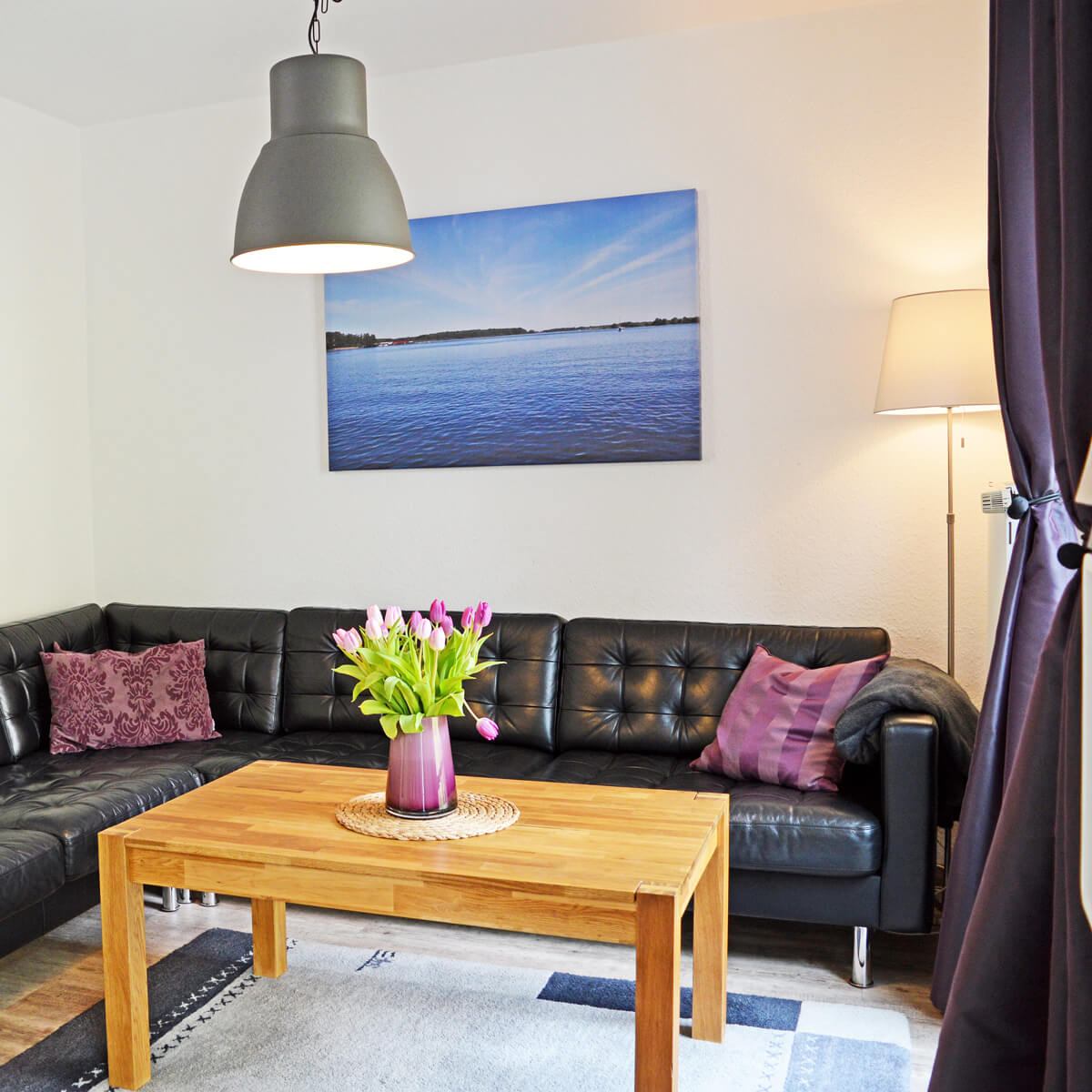 Wohnzimmer im Ferienhaus Fox Lenz mit Ledersofa, Holztisch und frischen Tulpen auf dem Tisch