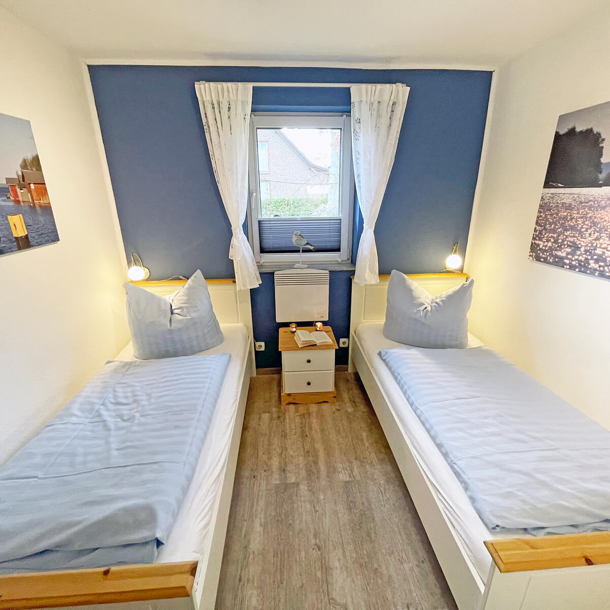 Helles Zweibettzimmer im Ferienhaus Fox Zislow mit blauer Wand und Fensterblick