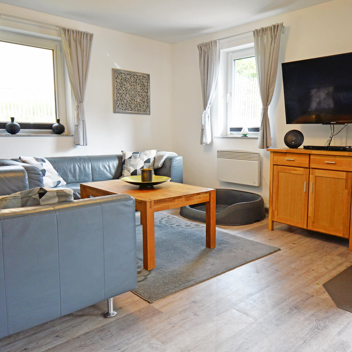 Helles Wohnzimmer im Ferienhaus Fox Zislow mit Sofa, TV und Hundebett