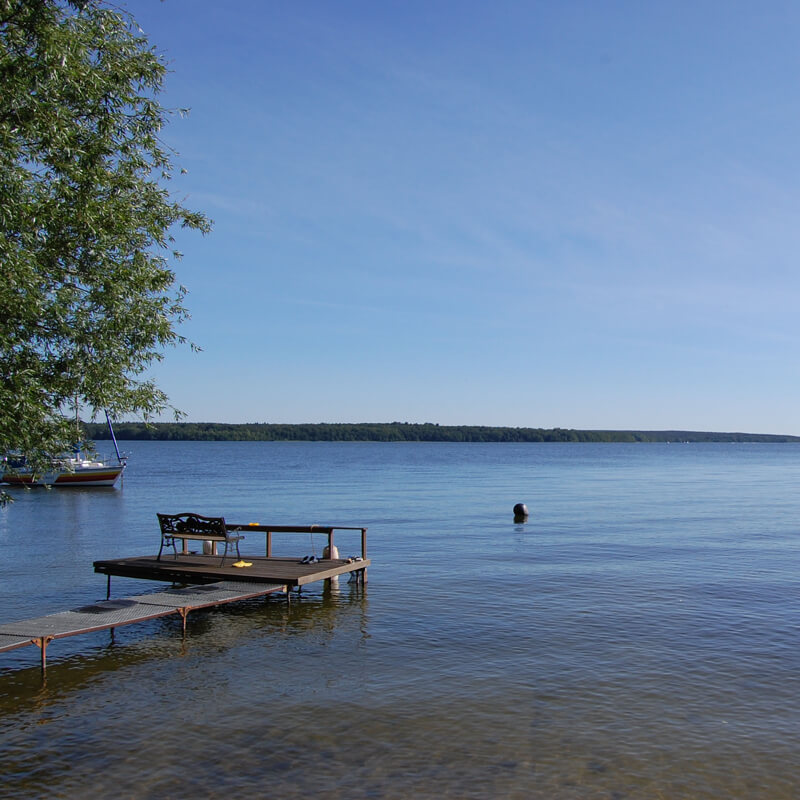 Badesteg am Plauer See mit Bank und Schwimmer im Wasser