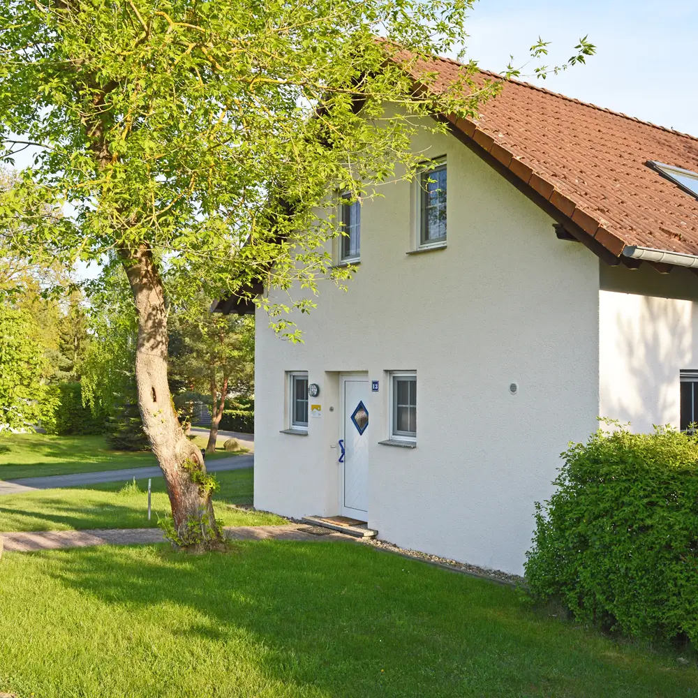 Weißes Ferienhaus am Plauer See mit rotem Dach, grünem Garten und idyllischer Lage