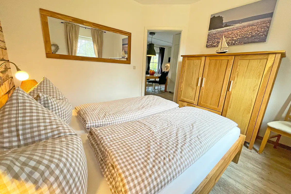 Gemütliches Schlafzimmer im Ferienhaus am Plauer See mit Holzschrank und karierten Bettbezügen