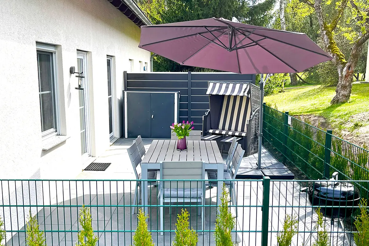 Sonnige Terrasse mit Strandkorb, Esstisch und Blumen – Ferienhaus am Plauer See