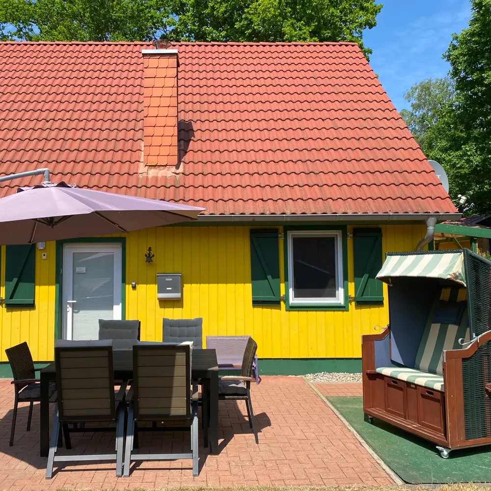 Gelbes Ferienhaus am Plauer See mit Terrasse, Sitzgruppe, Sonnenschirm und Strandkorb