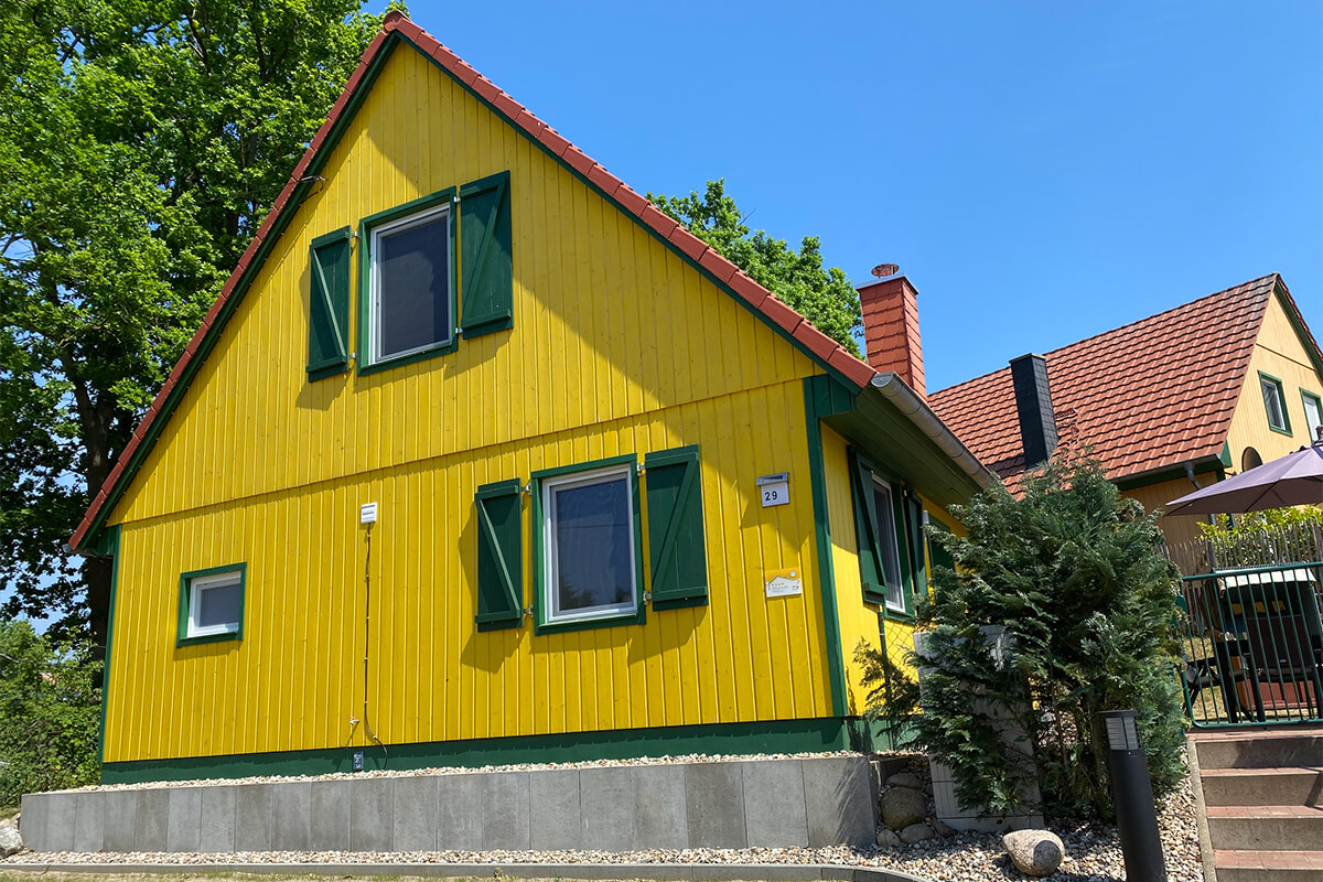 Gelbes Ferienhaus am Plauer See mit grünem Fensterläden und rotem Dach, familienfreundlich und hundefreundlich